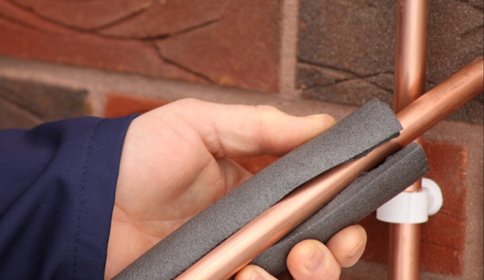 Person applying insulation foam to an copper pipe