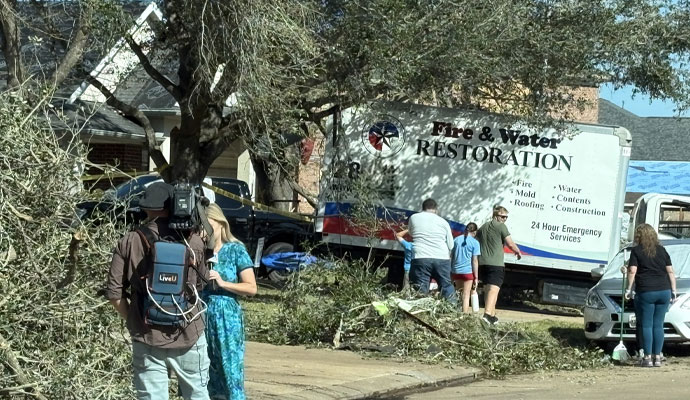 A white Fire Reconstruction Inc restoration truck parked at a disaster damaged site